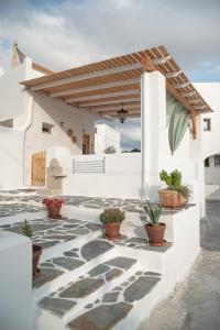 a white house with potted plants on a patio at Mythical Luxury Apartment in Naxos Chora