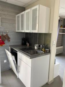 a kitchen with white cabinets and a sink at Le chalet de Thil 