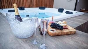 a table with two wine glasses and a cutting board with a hot tub at Vila Astra - jacuzzi gigante, telão 120 polegadas, próximo de tudo in Alto Paraíso de Goiás
