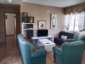 Sala de estar con 2 sillas azules y TV en Casa Los Geranios, en Pontevedra