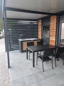 eine Terrasse mit einem Tisch, Stühlen und einem Waschbecken in der Unterkunft Hipo camp - Mobil home Sestrica in Pakoštane