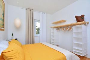 a bedroom with a yellow bed and white walls at Apartment Pepica in Postira