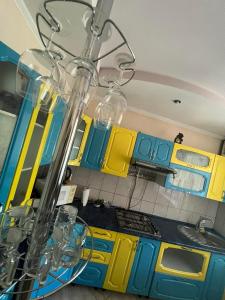 a kitchen with yellow and blue cabinets and a chandelier at Гостевой дом in Ciorescu