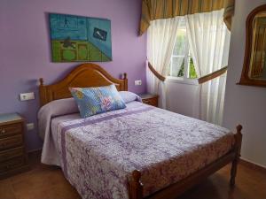 1 dormitorio con 1 cama con paredes de color púrpura y ventana en Casa Los Geranios, en Pontevedra