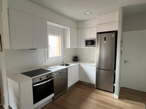 uma cozinha com armários brancos e um frigorífico de aço inoxidável em Apartaments La Pertusa em Corçà