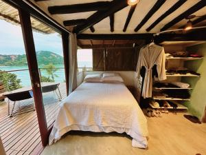 1 dormitorio con cama y vistas al océano en Suíte e sala - Vista Barra do Sahy en São Sebastião