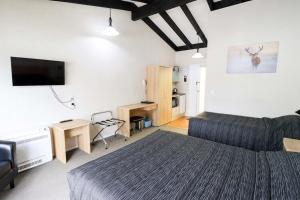 Dormitorio con cama, escritorio y TV en Aztec Motel, en Palmerston North