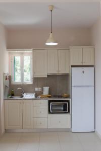 a kitchen with white cabinets and a white refrigerator at Kalami Studios in Kalami