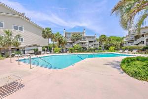 a swimming pool in front of a building with palm trees at New Listing! Seagrove Villa 3A - Luxurious Ocean View! in Isle of Palms