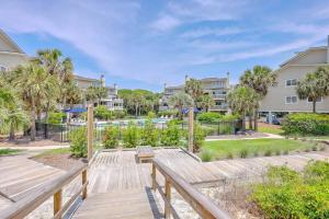 a wooden walkway with a bench in front of condos at New Listing! Seagrove Villa 3A - Luxurious Ocean View! in Isle of Palms