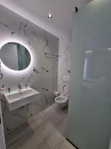 a bathroom with a sink and a toilet and a mirror at White Villa in Përmet