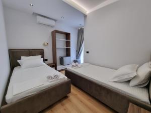 two beds in a small room with white walls and wooden floors at White Villa in Përmet