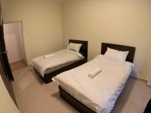 two beds with white sheets in a room at Bukit Bintang Fahrenheit88 Apartment by Sarah's Lodge in Kuala Lumpur