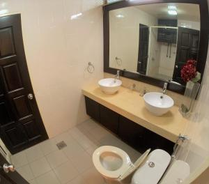 a bathroom with two sinks and a toilet and a mirror at Bukit Bintang Fahrenheit88 Apartment by Sarah's Lodge in Kuala Lumpur