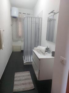 uma casa de banho branca com um chuveiro e um lavatório. em Kalisa Home, B&B e Casa Vacanza Palermo em Capaci