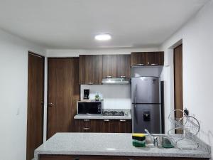 eine Küche mit Holzschränken und einem Kühlschrank aus Edelstahl in der Unterkunft Nuevo y amplio departamento con alberca y seguridad en el centro de Guadalajara in Guadalajara