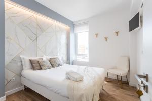 sypialnia z białym łóżkiem z geometrycznym zagłówkiem w obiekcie Lisbon Airport Suites w Lizbonie
