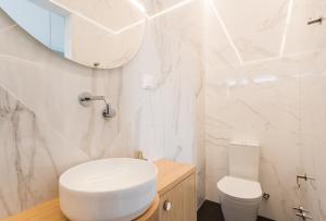biała łazienka z toaletą i lustrem w obiekcie Lisbon Airport Suites w Lizbonie