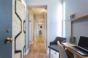 a hallway with a brick wall and a desk with a laptop at Lisbon Airport Suites in Lisbon