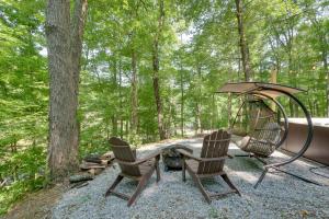 duas cadeiras e um baloiço na floresta em Tiny Home with Hot Tub By Mohican State Park! em Loudonville