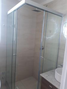 una ducha con una puerta de cristal junto a un lavabo en Céntrico y Cómodo departamento VIP, en La Paz