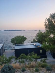 a building with a solar panel on the water at Hipo camp Mobil home Arta in Pakoštane