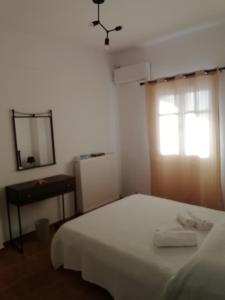1 dormitorio con cama, ventana y espejo en Andros Breeze, en Batsi