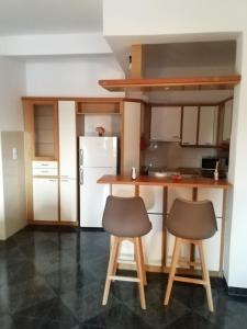 eine Küche mit zwei Hockern und einem weißen Kühlschrank in der Unterkunft Andros Breeze in Batsi