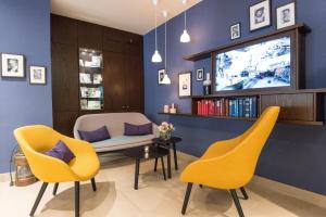 a living room with yellow chairs and a tv at Hotel Stella Maris in Hamburg