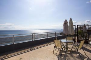 einen Balkon mit einem Tisch, Stühlen und Meerblick in der Unterkunft Scorpios Sea Side Hotel in Piräus