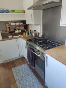 a kitchen with a stove and white cabinets at Room in private house near Reading University in Earley