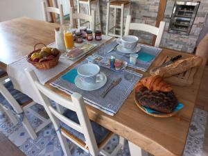 una mesa de madera con desayuno de pan y fruta en "chez Nat", en Chaillevette
