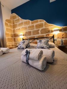 two beds in a room with a stone wall at Celeste Rooms in San Vito lo Capo
