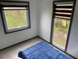 Casa Nueva en Parcela de Agrado في فالديفيا: غرفة نوم فيها نافذتين وسرير