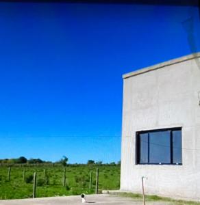 un edificio blanco con una ventana junto a un campo en La Deola en Concepción del Uruguay