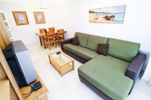 a living room with a green couch and a television at J Tramuntana Planet Costa Dorada in Salou