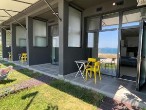 a patio with yellow chairs and a table on a house at Aliara Dilara Beach Apartments in Pomorie