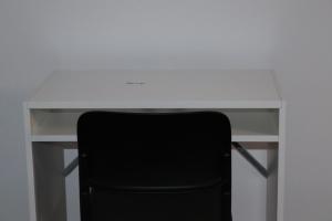 un escritorio blanco con una silla negra delante en OPULENT HOUSE London, en Dagenham