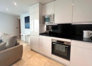 a kitchen with white cabinets and a microwave at Luxury 1 Bed - City Suites Ocean Spa Plaza in Gibraltar