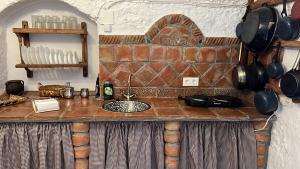une cuisine avec un comptoir, un évier, des casseroles et des poêles dans l'établissement la cueva de guadix, à Guadix