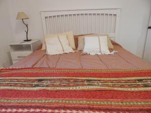 Una cama con dos almohadas y una manta. en Departamento Zona Residencial. wiffi. cochera en San Juan