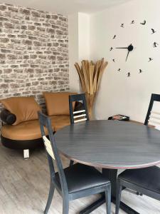 a dining room table with chairs and a clock on the wall at Nid douillet à La Bresse in La Bresse
