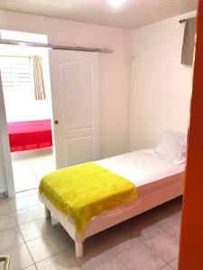 Un dormitorio con una cama con una manta amarilla. en La Kaz a Nana (F2 - Bas de Villa), en Le Gosier