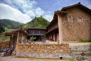 a stone house with a motorcycle parked in front of it at Dinh Đá H'Mông - Karsterly Rock Lodge in Dồng Văn