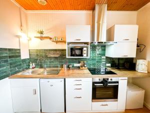 uma cozinha com armários brancos, um lavatório e um micro-ondas em II-Charmant Appartement au coeur de la ville em Guingamp