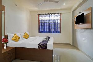 um quarto com uma cama, uma televisão e uma janela em SPOT ON 70112 Sri Saptagiri Bording Lodging em Bangalore