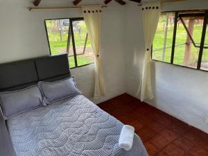 1 dormitorio con 1 cama en una habitación con ventanas en Casa campestre Ubate, en Ubaté