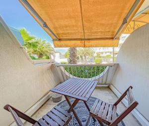 a picnic table and two chairs on a balcony at Le soupir des palmiers. Idéal couple, piscine, mer in La Grande-Motte