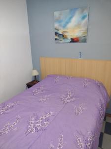 Una cama púrpura con un edredón púrpura y una pintura en Centrico Pichincha cercano al rio en Rosario