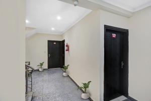 zwei schwarze Türen in einem Raum mit zwei Pflanzen in der Unterkunft OYO Flagship Hotel Blue Orchid in Neu-Delhi